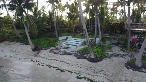 ShakaBrah-beach-Café-and-resort-on-Siargao-island-at-sunset-with-tropical-sand-beach-and-coconut-palm-tree-swing