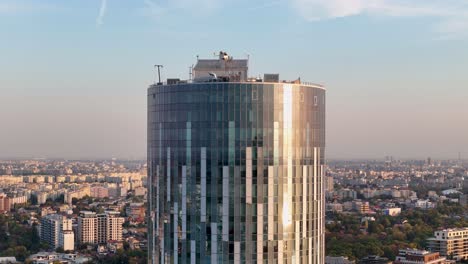Aerial-Close-Up-Of-A-Tall-Office-Building-With-A-Stunning-Sunset-In-The-Background,-Bucharest,-Romania