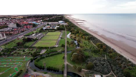 Aerial-video-footage-displays-the-elegance-of-a-sunset-over-Skegness,-a-delightful-seaside-town-in-the-UK,-showcasing-the-town,-promenade,-pier,-and-coastline
