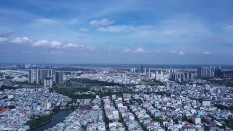 Slow-pan-and-reveal-of-Ho-Chi-Minh-City,-Vietnam-on-clear-sunny-day-featuring-Saigon-River-and-city-skyline-from-drone