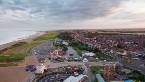 From-above,-video-footage-reveals-a-breathtaking-sunset-scene-over-Skegness,-a-picturesque-seaside-town-in-the-UK,-featuring-the-town-itself,-the-promenade,-the-pier,-and-the-coastline