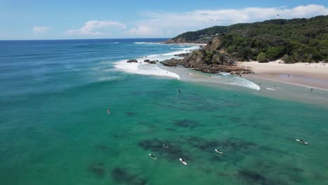 Aerial-View-Of-Surfers-Floating-In-The-Ocean-In-Clarkes-Beach,-NSW,-Australia---drone-shot