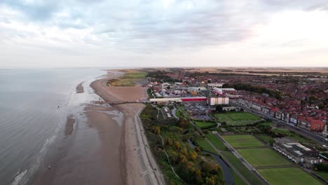Above-the-horizon,-video-footage-presents-the-splendor-of-a-sunset-over-Skegness,-a-delightful-coastal-town-in-the-UK,-featuring-the-town,-promenade,-pier,-and-coastline