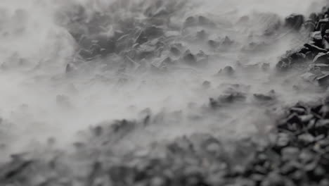 Nahaufnahme-Eines-Nebels,-Der-Durch-Schwarze-Steine-Aufsteigt-Und-Den-Bildschirm-Bedeckt