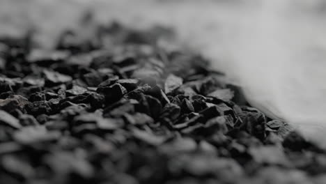 Detailed-Close-up-Macro-Shot-Of-White-Mist-Slowly-Covering-Black-Stones