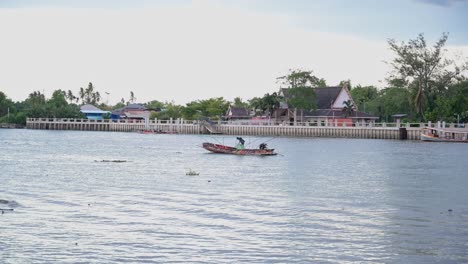 Un-Barquero-Ancló-Su-Bote-Motorizado-De-Madera-En-Medio-Del-Ancho-Río-Mae-Klong-Mientras-Prepara-El-Chaleco-Salvavidas-Para-Sus-Pasajeros,-En-La-Provincia-De-Samut-Songkhram-En-Tailandia.