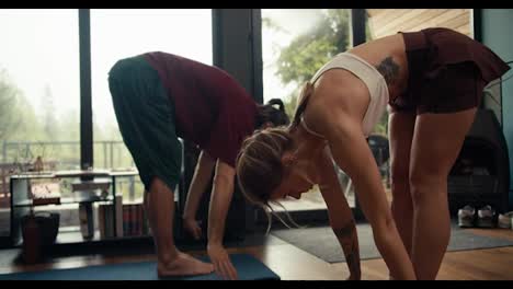 A-brunette-guy-in-a-red-T-shirt-and-a-blonde-girl-in-a-white-top-are-doing-yoga-and-doing-exercises-in-an-industrial-house-overlooking-a-green-forest