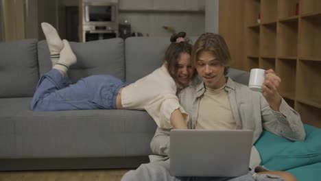 Young-adult-couple-talking-using-laptop-computer-at-home-watching-video