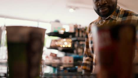 Close-up-shot-of-a-Black-man-choosing-one-of-two-items-on-the-floor-in-a-supermarket.-The-choice-of-goods-in-the-store,-consumer's-view