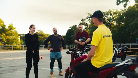 3-students-at-school-interact-with-a-professional-motorcycle-driver.-Driving-instructor-in-a-yellow-t-shirt-communicates-with-students