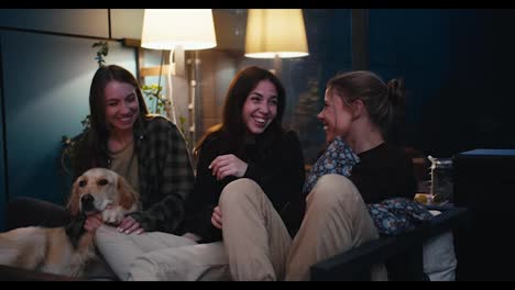 Happy-trio-of-girls-are-sitting-on-the-couch-chatting-and-having-fun.-Active-communication,-cheerful-and-cozy-evening