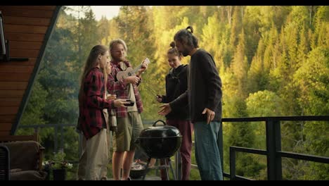 A-group-of-friends-cook-food-on-the-grill-and-listen-to-the-guitar-at-a-barbecue-picnic-in-a-country-house-overlooking-the-forest-and-mountains