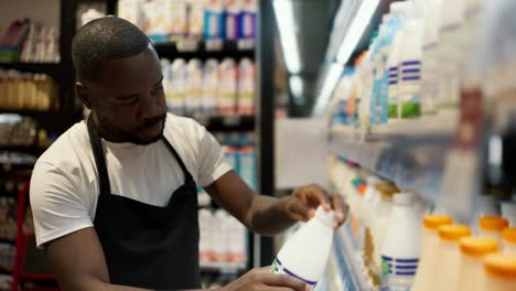of-a-Black-man-in-a-white-t-shirt-and-black-apron-inspecting-tvoar-at-a-dairy-counter.-Video-filmed-in-high-quality