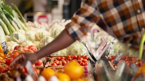 Close-up-shot-of-a-Black-man-in-a-plaid-shirt-choosing-vegetables-at-a-supermarket-counter.-View-of-juicy-and-rich-summer-vegetables.-Video-filmed-in-high-quality