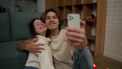Lovely-couple-sitting-on-the-floor-together,-taking-selfie-with-smartphone