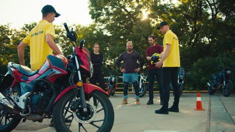 Two-instructor-guys-in-a-driving-school-communicate-with-their-students.-A-group-of-motorcyclists-stand-at-the-driving-range-along-with-motorcycles