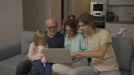 Children-and-grandpa-are-laughing-together-while-using-a-laptop,-watching-video