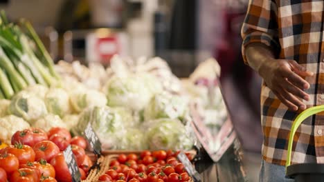 Close-up-shot-of-a-Black-man-choosing-vegetables-at-a-supermarket-counter.-Review-on-juicy-tomatoes-in-the-supermarket