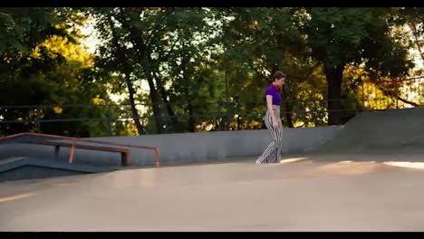 A-young-girl-with-a-short-haircut-in-a-purple-top-and-striped-pants-rides-on-roller-skates-in-a-skate-park-on-a-concrete-surface