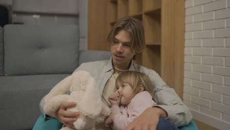 Father-and-daughter-play-together-with-soft-toy,-sitting-on-the-chair