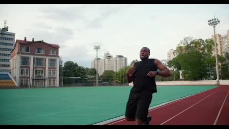 A-Black-skinned-man-in-black-sportswear-runs-a-speed-race-after-which-he-looks-at-the-time-and-rests