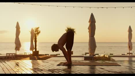 The-guy-stands-up-on-his-hands-during-a-yoga-and-meditation-class-on-a-sunny-beach-in-the-morning.-Healthy-way-of-life,-harmony