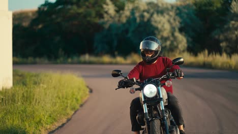Ein-Mann-In-Einem-Roten-Pullover-Und-Einem-Motorradhelm-Dreht-Bei-Sonnigem-Wetter-Effektiv-Auf-Einem-Motorrad-Auf-Der-Straße.-Motorradfahren-Als-Hobby