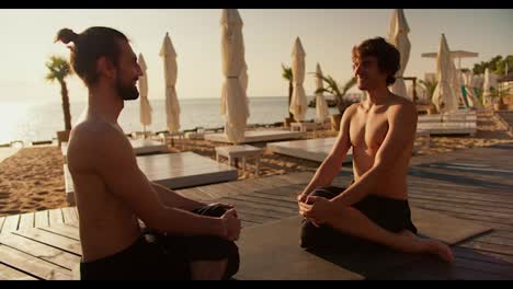 Zwei-Männer-Sitzen-Morgens-An-Einem-Sonnigen-Strand-Und-Meditieren.-Harmonie-Von-Körper-Und-Geist