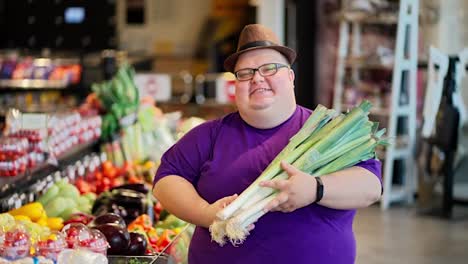 Portrait-of-a-happy-overweight-man-in-a-purple-T-shirt-and-a-brown-hat-and-glasses-who-holds-a-bunch-of-shallots-in-his-hands-and-poses-against-the-background-of-a-large-supermarket