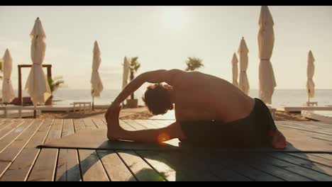 The-guy-is-stretching-and-doing-stretching-on-a-sunny-beach-in-the-morning.-Morning-exercise-for-health