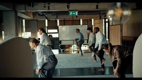 Overview-of-a-group-of-business-people-in-business-attire-doing-yoga-during-a-break-at-work-in-the-office.-Taking-care-of
