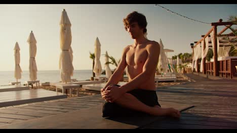 The-guy-took-a-special-position-for-yoga-and-meditation.-Zen-style-in-the-morning-on-the-beach