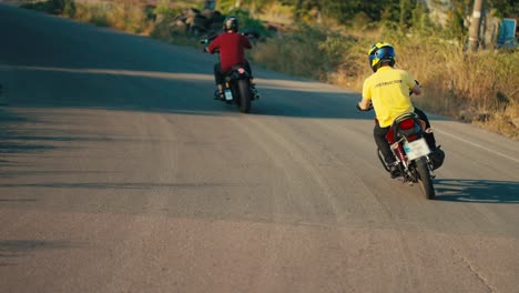 An-instructor-in-a-yellow-T-shirt,-together-with-his-motorcycle-driving-student,-are-turning-at-the-corner-of-the-road.-Teaching-how-to-ride-a-motorcycle