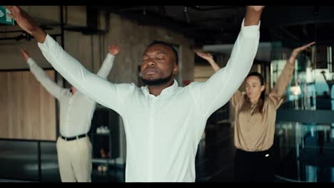 A-Black-business-man-in-a-white-shirt-is-doing-yoga-with-his-colleagues-in-the-office.-Take-a-break-from-work-to-maintain-spiritual-strength-and-stability