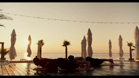 Zwei-Männer-Machen-Wellness-Yoga-Am-Strand-Bei-Sonnenaufgang.-Sport-Und-Morgengymnastik