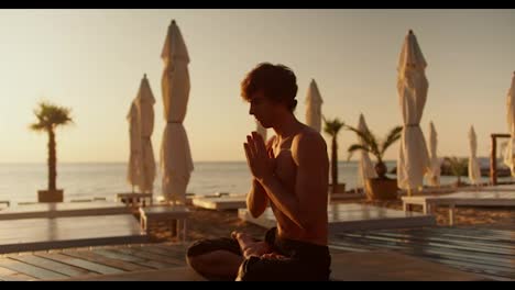 The-guy-meditates-on-a-special-mat-on-a-sunny-beach-in-the-morning.-Harmony-of-body-and-mind.-Zen-style
