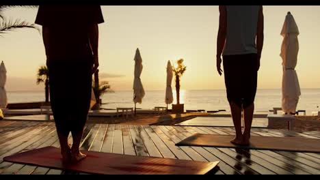 Zwei-Männer-Beobachten-Den-Sonnenaufgang-Und-Meditieren-Im-Stehen.-Zen-Morgen-Am-Sonnigen-Strand