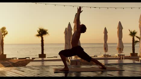 Ein-Mann-Mit-Nacktem-Oberkörper-Streckt-Sich-Morgens-Am-Strand-Und-Macht-Yoga--Und-Meditationsbewegungen