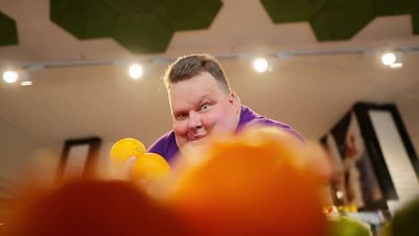Happy-man-with-a-cheerful-and-thirsty-grimace-chooses-oranges-right-from-the-counter.-The-man-sticks-out-his-tongue-a-little-and-takes-a-third-orange-for-himself