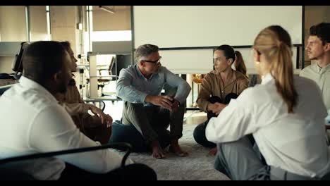 Gruppentherapie:-Menschen-In-Geschäftsanzügen-Kommunizieren-Untereinander,-Während-Sie-Im-Büro-Auf-Einer-Matte-Sitzen