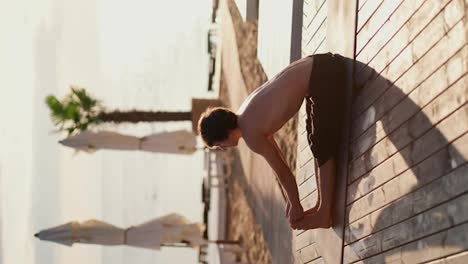 Vertikales-Video:-Ein-Mann-In-Schwarzen-Shorts-Macht-Dehnübungen-Und-Yoga-An-Einem-Sonnigen-Strand