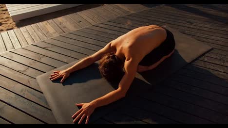 The-guy-took-a-special-pose-for-yoga-and-stretching-on-a-special-mat-on-a-sunny-beach-in-the-morning