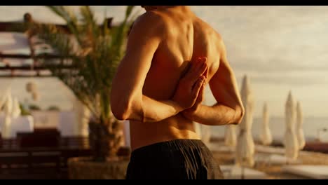 Kerl,-Der-Morgens-An-Einem-Sonnigen-Strand-Dehnübungen-Macht-Und-Meditiert.-Der-Yogi-Hält-Seine-Hände-In-Einer-Speziellen-Yoga-Pose-Hinter-Dem-Rücken