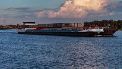 Cargo-ship-sailing-on-Dutch-rivers-carrying-containers-of-goods-at-sunset