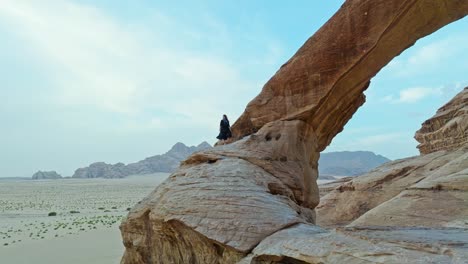 Female-Tourist-At-Natural-Arch-Al-Kharaza-In-The-Desert-Of-Wadi-Rum-In-Aqaba,-Jordan