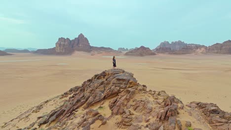 Orbitando-Sobre-Una-Mujer-Parada-En-Las-Rocas-Geológicas-De-Wadi-Rum-En-El-Sur-De-Jordania,-Oriente-Medio