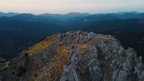 A-drone-pushes-over-a-grey-stone-peak-in-the-Pico-De-Los-Reales,-Estepona,-Spain