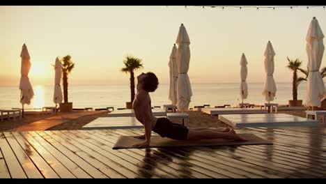 A-young-guy-with-a-naked-torso-does-yoga-and-gets-up-on-his-hands-at-sunrise.-Yoga-and-zen-style