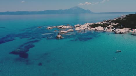 Luftüberführung-Strand-Von-Kavourotrypes-In-Chalkidiki,-Griechenland-Mit-Vielen-Menschen,-Die-In-Klares,-Blaues-Wasser-Springen