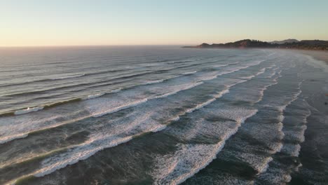 Calming-high-aerial-of-crashing-waves-along-beach,-peaceful-sunset-scene